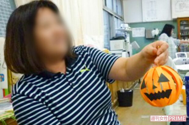 ハロウィンのかぼちゃの飾りを持つA教員。前任学校のホームページより（'15年10月）