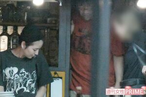 奥の個室から出てきて靴をはく長澤。アメリカのロックバンドのTシャツを着ていた