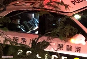 パトカーに乗せられた川容疑者（奥）。顔はマスクで隠れていた（読者提供）