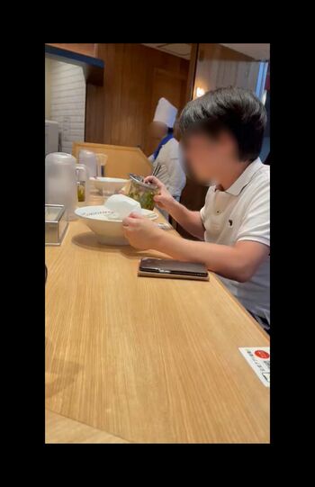 カウンター席に座る、白のポロシャツを着た男性