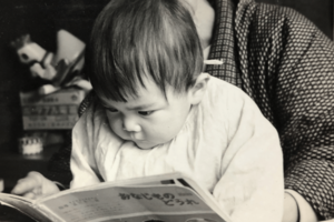 小さいころ、信友さんは父が仕事から帰るとすぐに父のひざに座り、本を読めと言っていた