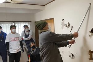 『佐田工務店』メンバーがハンマーで壁を壊したあと、最後にバールで壁を破壊するヒロシ（佐田のYouTubeチャンネルより）