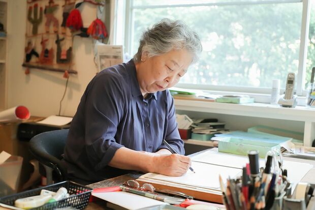 亡き父から受け継いだ机で今も描き続けている。子どもたちのように、楽しみながら描くことが大切という
