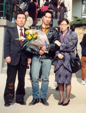  【写真】高校の卒業式で両親と（奨学会提供）