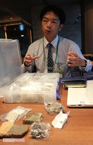 熱線の直撃を受けて表面が泡立った被爆瓦など、川から引き上げた遺品を並べて話す嘉陽さん