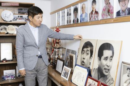 事務所の大先輩である萩本欽一、故・坂上二郎さんのパネルの前で。「要所要所で萩本さんからいただいたアドバイスのおかげでここまでくることができました」 撮影/矢島泰輔