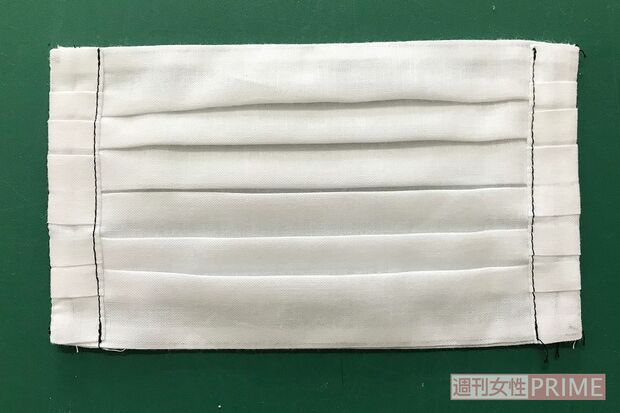 (6)大きい布が下になっている状態で(1)の縫い目から三つ折りにし写真のように縫う。ここにマスクゴムが通る。