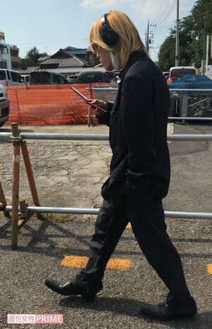 ヘッドホンにくわえタバコでガラケーをいじる成島明彦容疑者（昨年8月、住民提供）