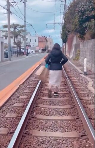 江ノ電の線路内をリズミカルに歩くインフルエンサー女性