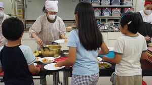 ボランティアがよそう料理を子どもたちが自分で取りにいく