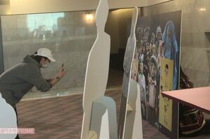 パネルに顔をはめた永を撮影する小池