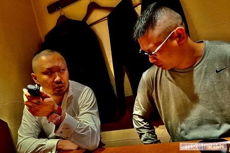 居酒屋で真剣な会話をする山中組長(左)と佐々木被告(右)