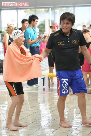 澤田真太郎コーチに手を引かれてプールサイドへ向かう長岡三重子さん