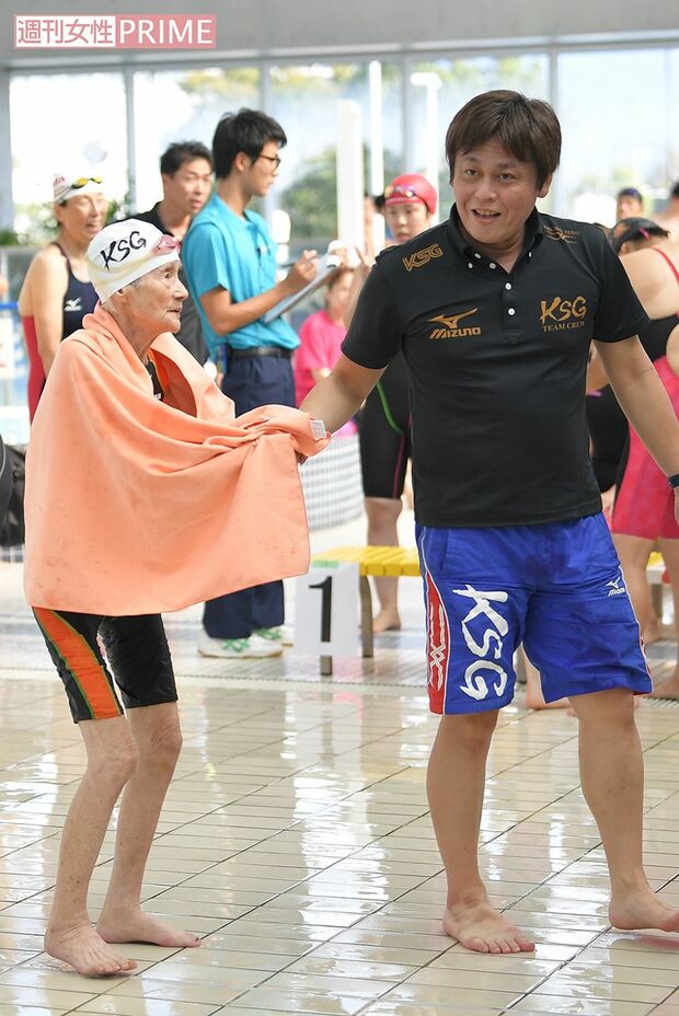 澤田真太郎コーチに手を引かれてプールサイドへ向かう長岡三重子さん