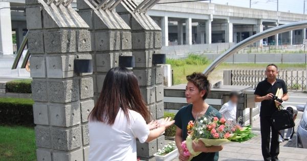 校舎を後にした佐藤を生徒が追いかけて、感謝の花束を渡す場面も（熊本市立総合ビジネス専門学校提供）