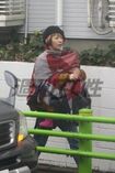 カラフルな大判のストールで、抱いている長女を雨から守るカエラ