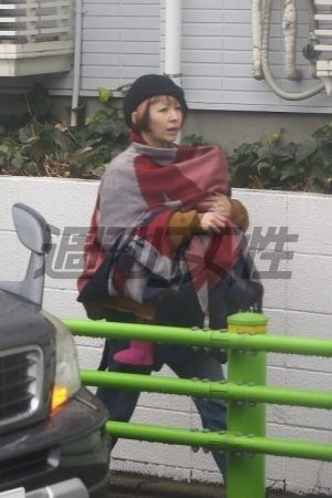  カラフルな大判のストールで、抱いている長女を雨から守るカエラ