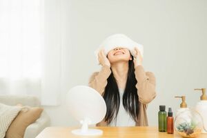 目をタオルで温める女性（※画像はイメージです）