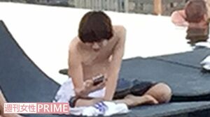 シンガポールのプールサイドで携帯電話を操作する伊野尾