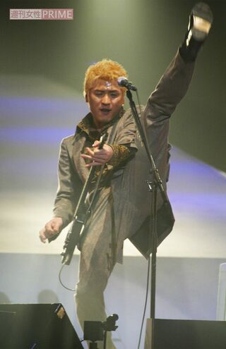 ギターを弾きながら足を高く上げる吉川晃司（2004年、20周年記念ライブにて）