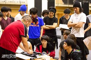  【写真】ペダステの魅力のひとつでもある舞台装置の動きを模型で説明する西田氏。動きのパターンがいくつもあるので、自分たちだけで通用する独特の愛称で区別している