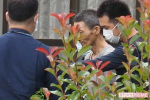 実況見分後、うつむいたまま自宅から出てきた容疑者(中央)=22日