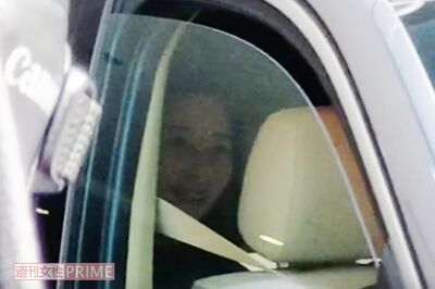 3月7日、夫が逮捕された件で直撃取材を受ける三浦瑠麗氏。車内でも笑みを浮かべている
