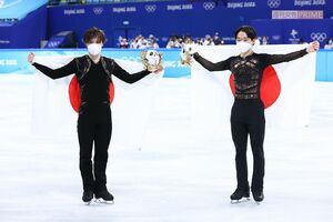 北京五輪公式マスコット『ビンドゥンドゥン』を手に、国旗を背負う宇野昌磨（左）と鍵山優真（右）（JMPA代表撮影）