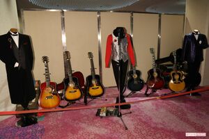 お別れ会の会場に飾られた谷村新司さんの歴代衣装やギター。中央は2022年にアリスのライブで着用。赤いシャツと銀のベストが特徴