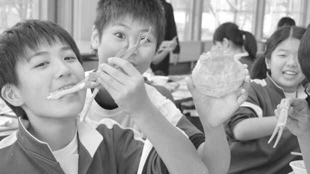 最近では地元の高級食材が給食に出ることも。写真は給食のズワイガニをほおばる富山県の小学生。うらやましいかぎりだ