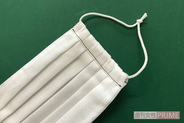 (7)ゴムを通す。長さは、自分の顔に合わせてみてからカット。マスクのプリーツにひっかからないように注意しながら通し、2本一緒に結び、結び目をマスクの中に隠す。