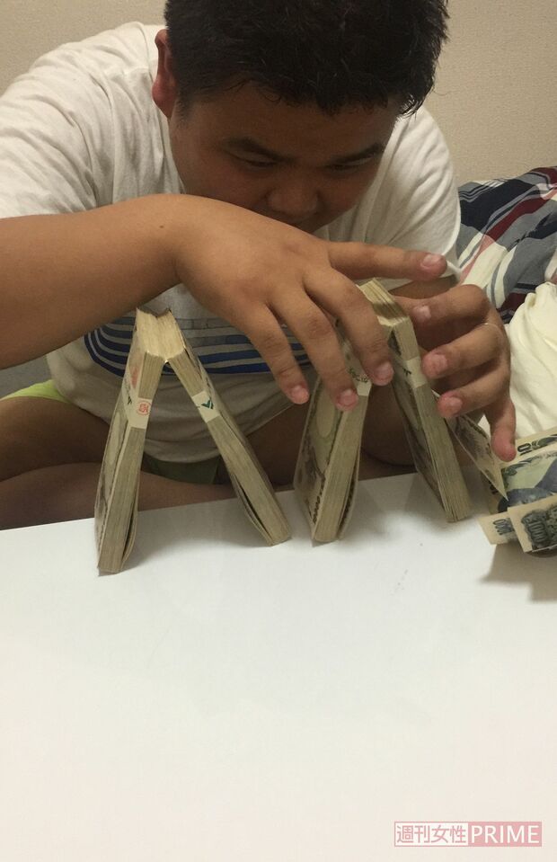 札束でピラミッドタワーを作って遊んでいる西容疑者（読者提供）