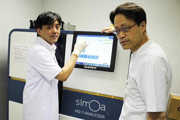 研究チームの徳田隆彦教授（右）と建部陽嗣特任助教（左）。中央に写るのが分析機器