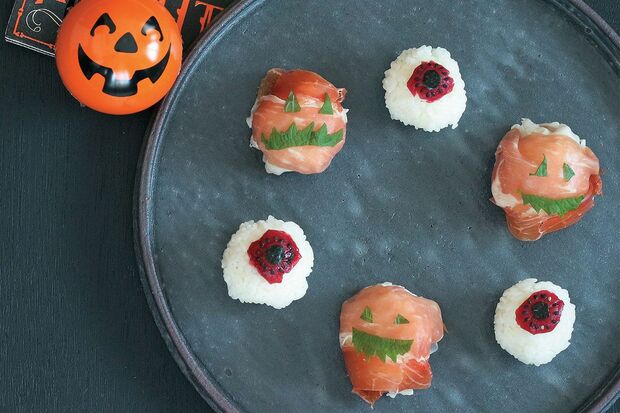【ホラー手まり寿司】ひと口サイズに握った酢めしに、ハロウィン風のデコを施した可愛い一品。（右）目玉は梅干しの果肉、焼きのり、黒ごまで、（左）ジャックオーランタンは生ハムとカットした青じそで飾る。『可愛くって ホラーで 美味しい！ キモめし』より