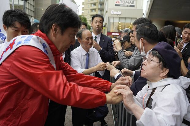 応援演説に駆け付けた地元住民とグータッチをする菅氏。手があまり上がっていない