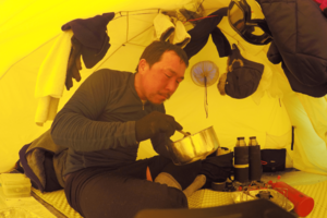 テント内で食事をとる荻田さん