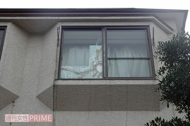 容疑者の自宅アパート。窓ガラスには大きなヒビ割れをテープでふさいだ跡が見える