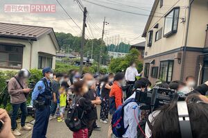 ニシキヘビの捜索をアパートの前で見守る近所の住民や報道陣＝22日午後4時半すぎ