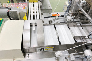 【3断裁】奥のカッターで断裁され、流れ落ちてくる。マスクらしい形状に