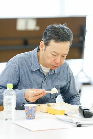 シュウマイ弁当を黙々とかきこむ板尾。「お笑いはひとりでもできるけど、映画監督は多くのスタッフを納得させて動かさなくてはいけない」と監督業の難しさを。「シリアスな役よりコメディーのほうが難しいと思いますよ。コメディーは面白いか、面白くないかで評価がはっきり分かれますから」とお笑い出身のプライドもにじませた。撮影／森田晃博