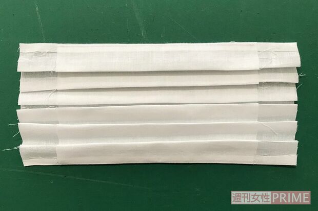 (4)プリーツをたたむ。上下に二つ折りにしてアイロンをかけ、真ん中に折り目をつけてから、そこに向かって写真のようにたたむ。たたむ幅は7mm～1cmくらいの間で適当でOK。折り目はアイロンでひとつずつしっかり押さえながらつけるとやりやすい。