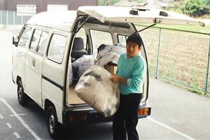 刺しゅうを外注先に依頼し、完成品を持ち帰る入社当時の鈴木和夫さん