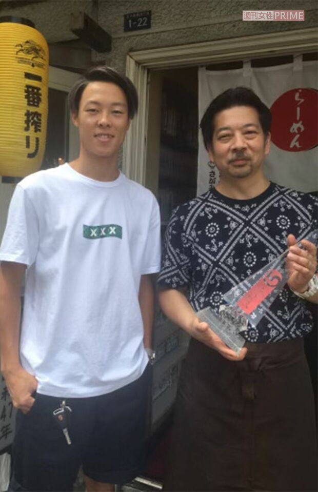 小林のトロフィーを持つ『らーめん味坊』の店主・堀さん（右）と小林。お気に入りのメニューは味噌ラーメン