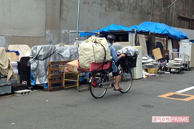 大量な空き缶を積んで自転車をこぐホームレス