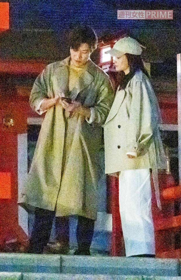 2月中旬、『シティーハンター』ロケでスマートフォンを見ながら、黒木メイサ（写真右）と打ち合わせをする鈴木亮平