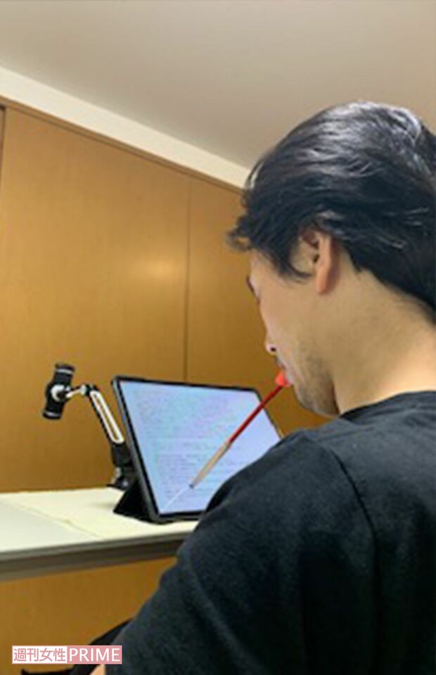 口にくわえたタッチペンを使い、タブレットでイラストを描いたり、原稿を執筆する