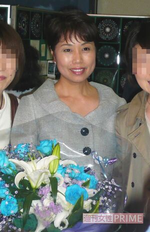 2009年、講演会後にファンと記念写真を撮る木村方子さん。手には青いバラの花束が