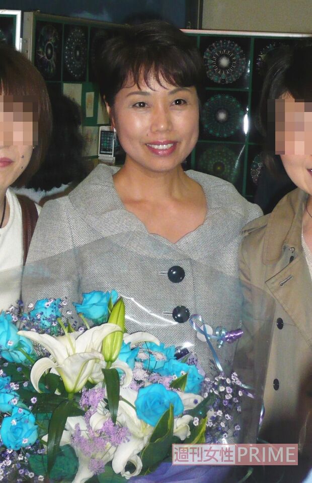 2009年、講演会後にファンと記念写真を撮る木村方子さん。手には青いバラの花束が