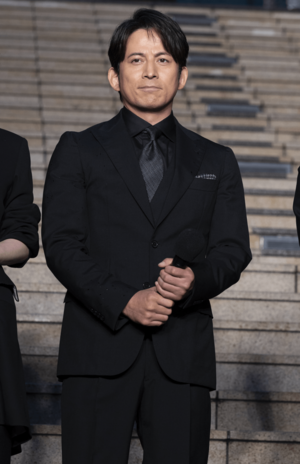 5段階中、上から2番目の茶帯を有する岡田准一。スーツ越しでもわかるがっしりとした胸厚