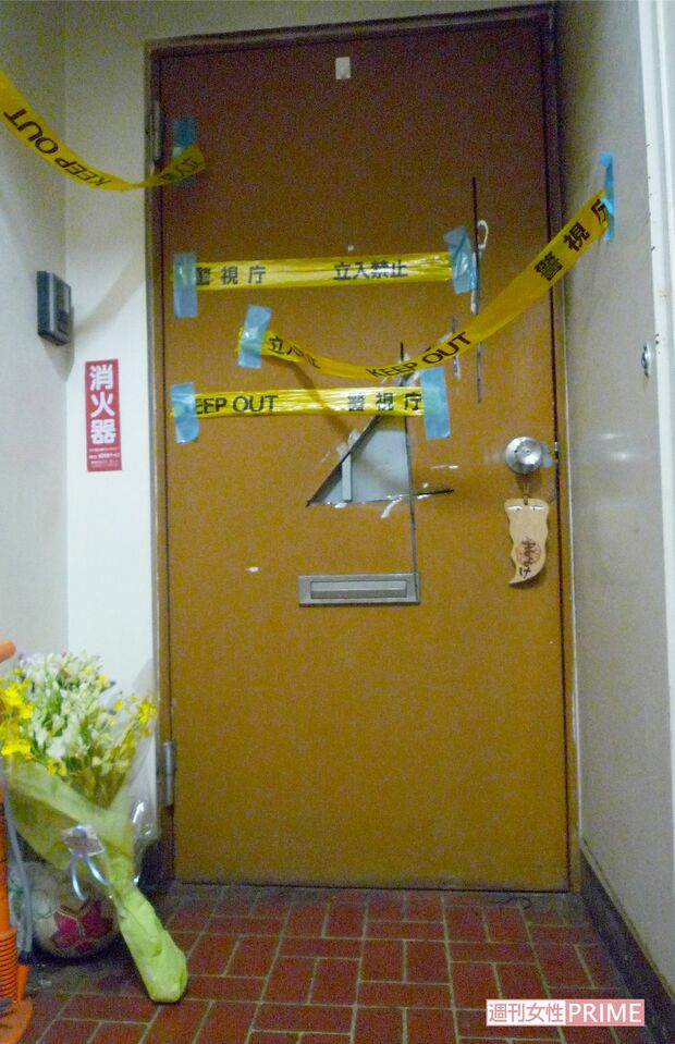 消化活動の生々しい痕跡を残す、麻衣さん宅の玄関ドア。玄関先には麻衣さんの死を悼んで花束が手向けられていた